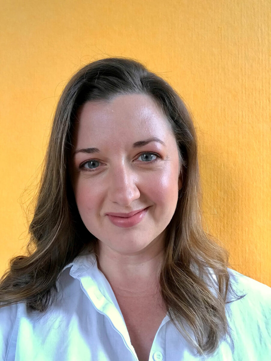 A woman smiling with wavy hair.