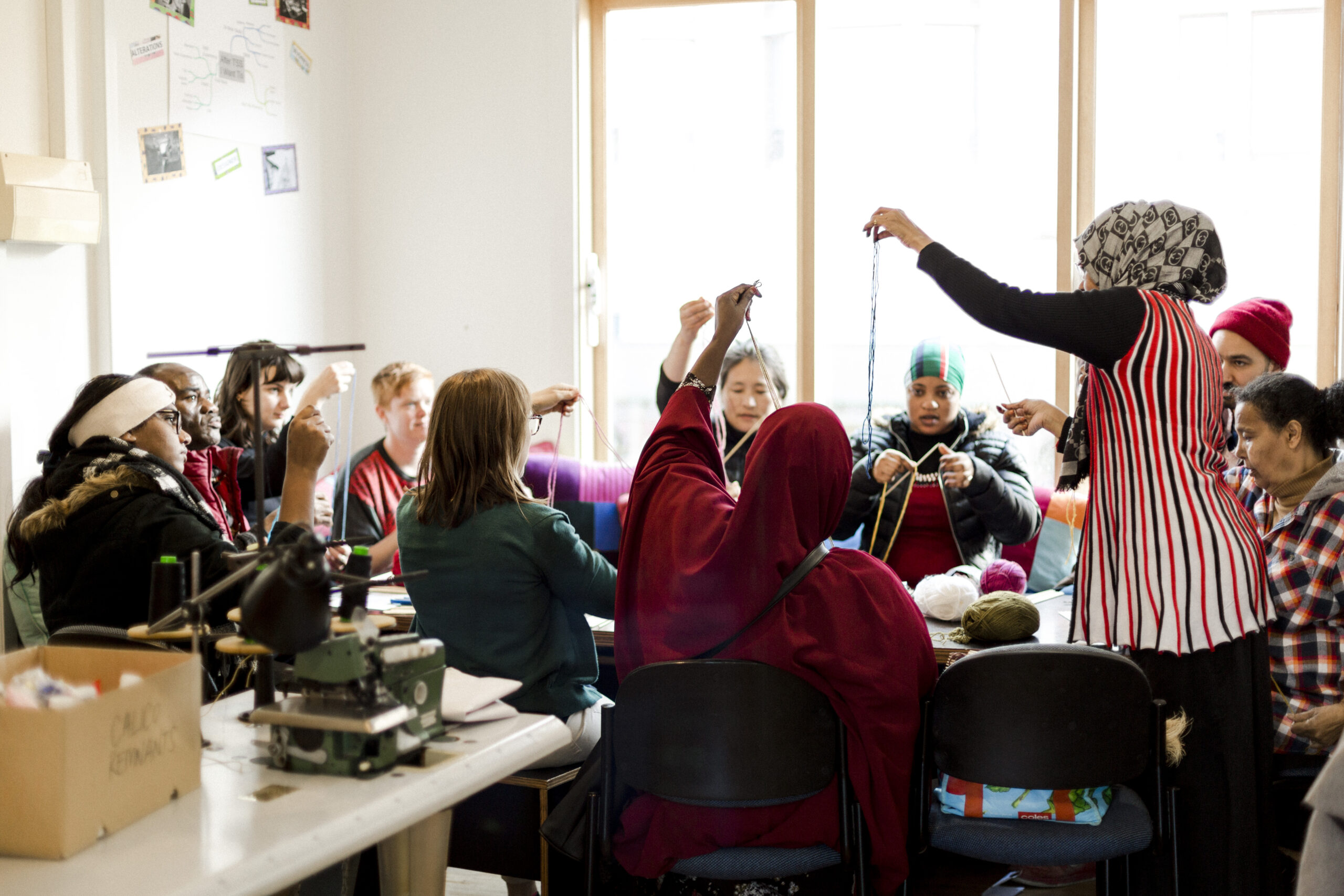 A group of diverse people learning how to knit.