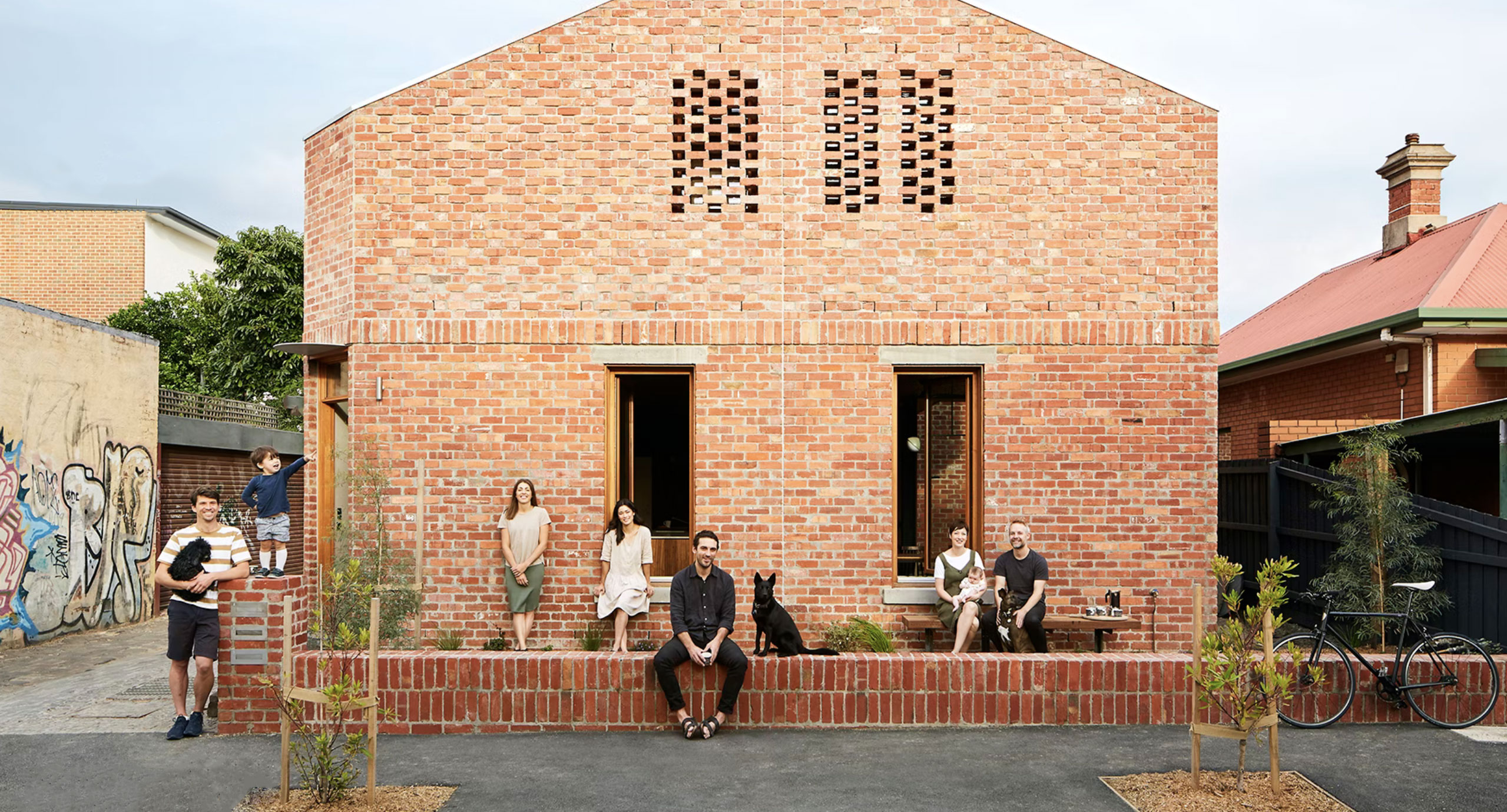 Red brick townhouses with families in the front yard.