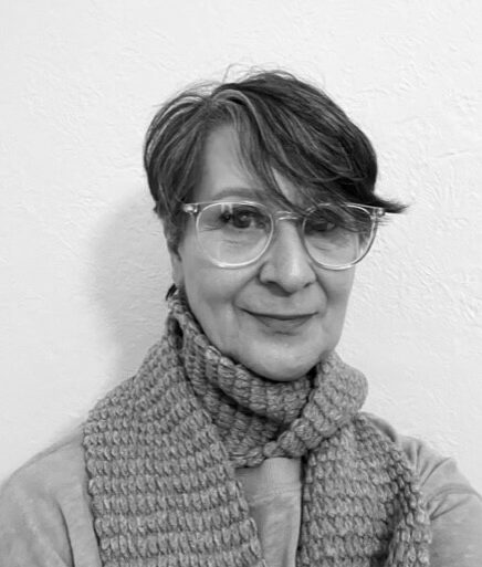 A woman smiling with short hair and glasses.