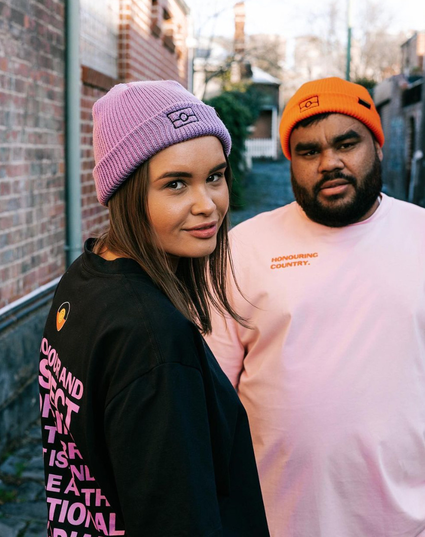 Two indigenous peoples wearing t-shirts with honouring country slogans.
