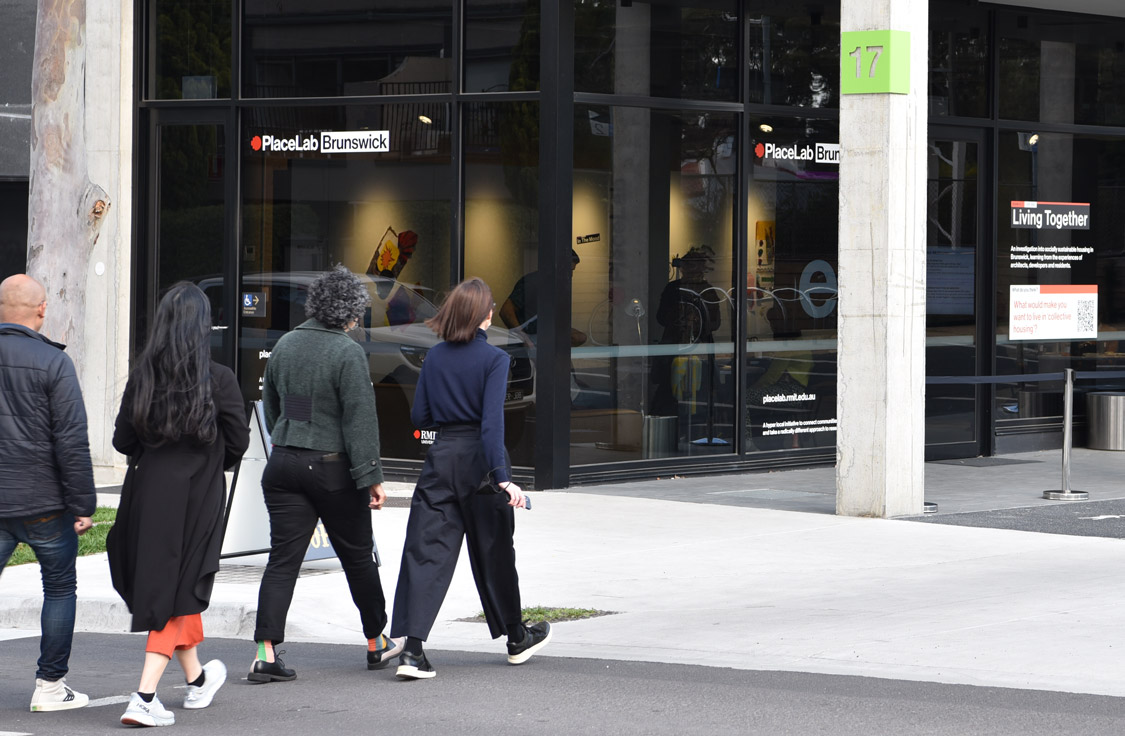 Four people walking towards the RMIT PlaceLab research studio.