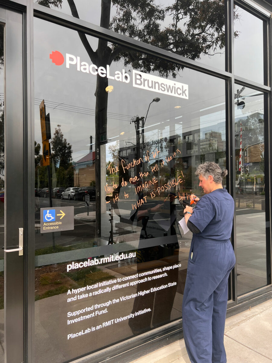 The artist writing on the glass wall at PlaceLab.