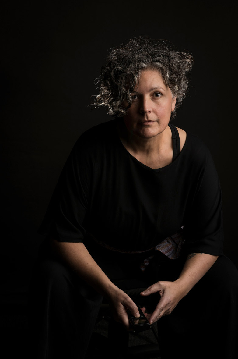 A photo of a woman with short curly hair and a camera.