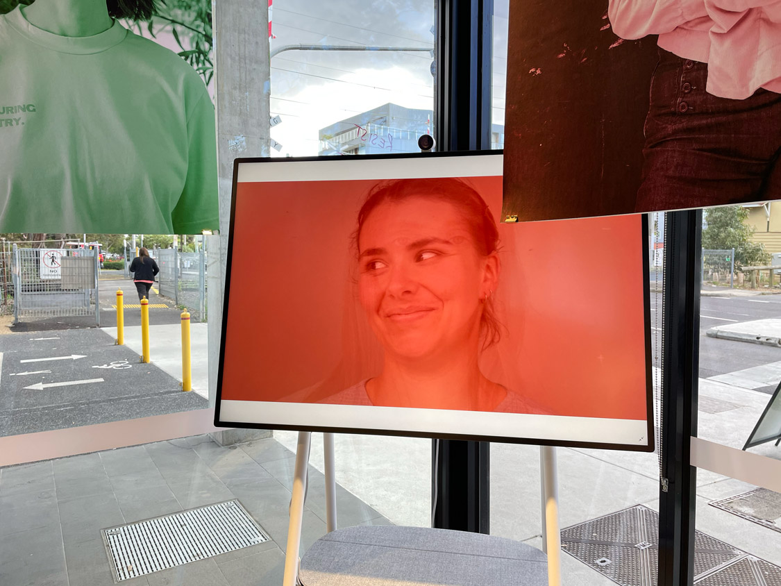 A young woman on a tv screen smiles.