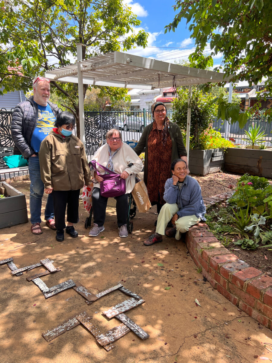 A group of people outside in the garden by the art work.