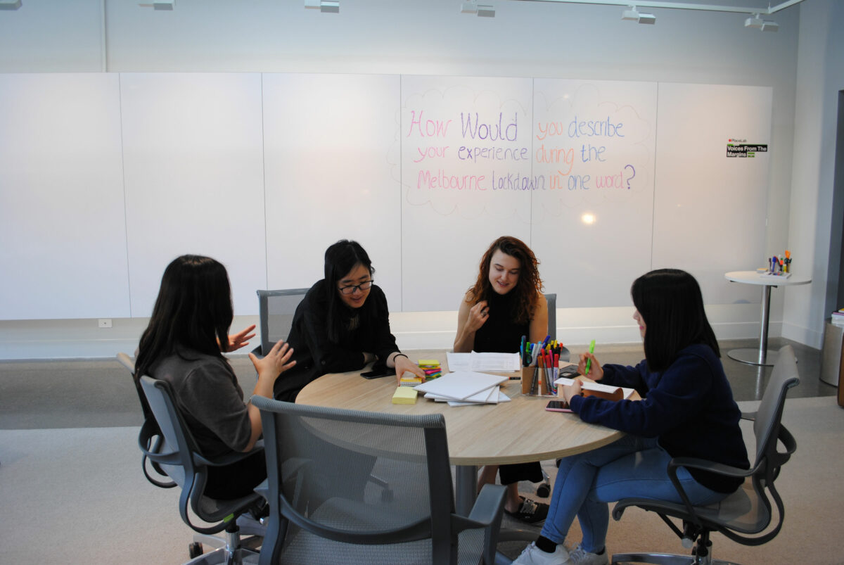 A group of 4 people sit around a round table talking.