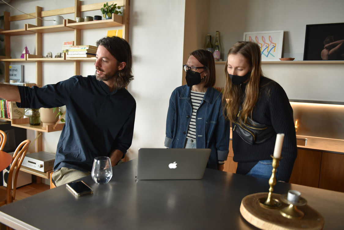 Three people in a kitchen, one person is pointing at something off screen.