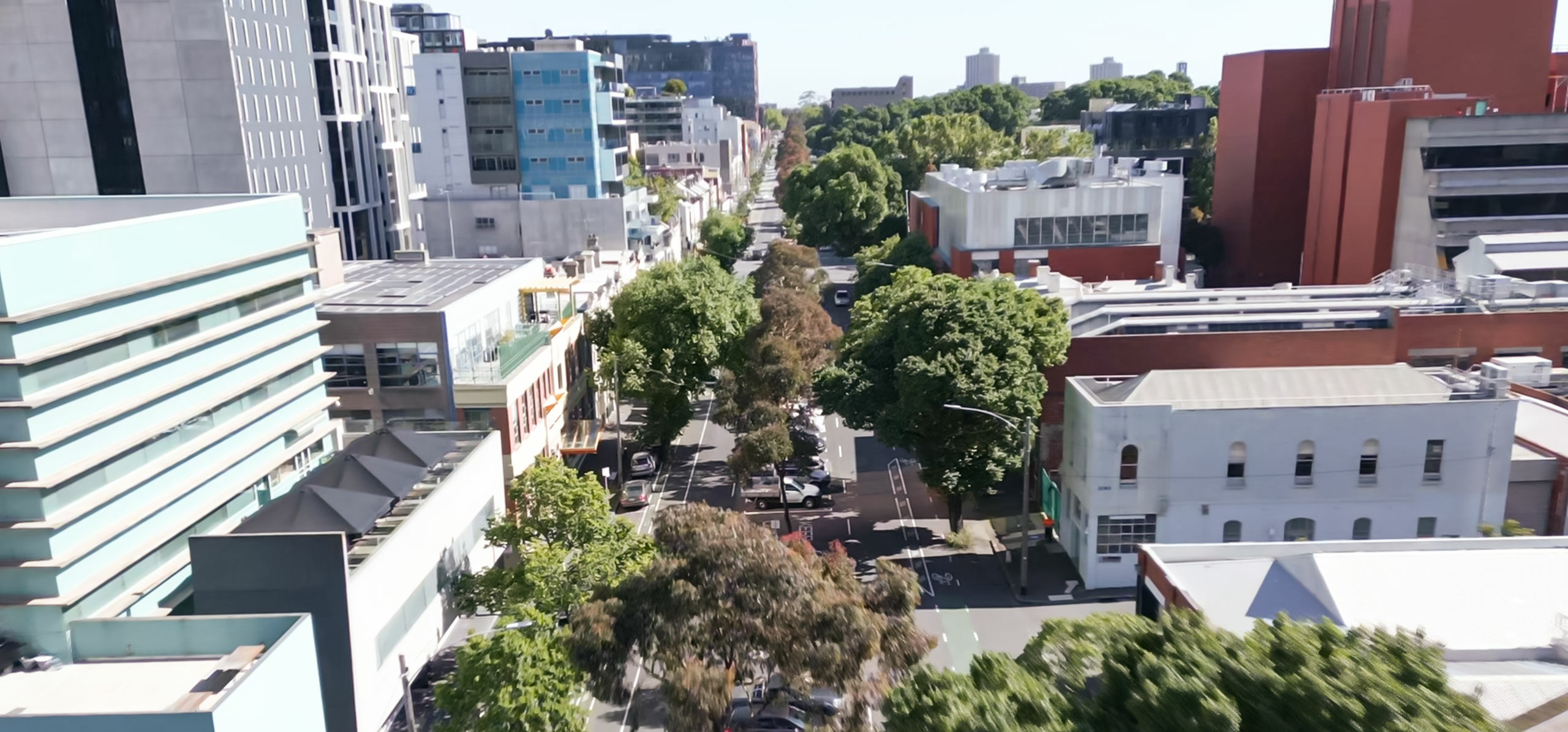 View of street with tall buildings, trees and cars