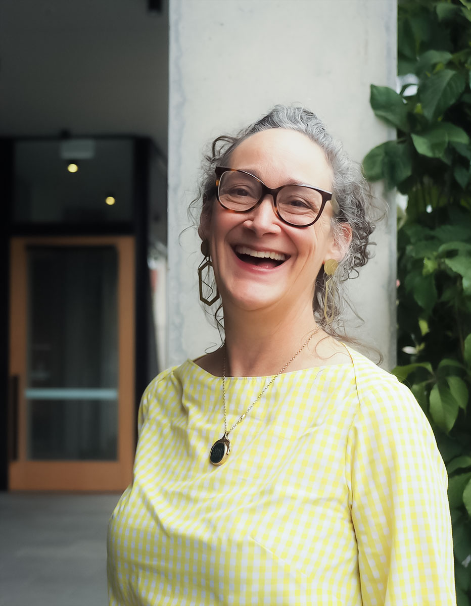 Woman smiling wearing glass and necklace.